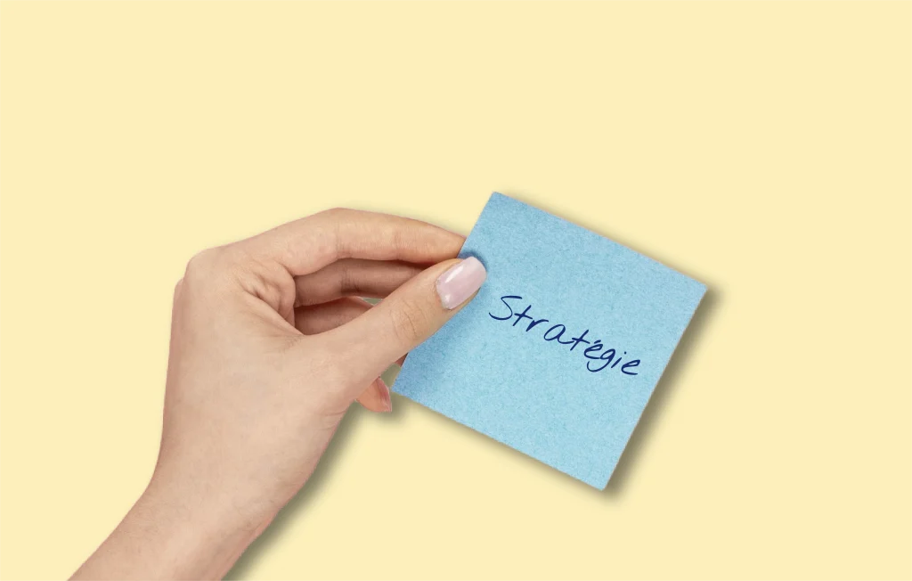 Main qui tient un post-it bleu écrit "Stratégie"